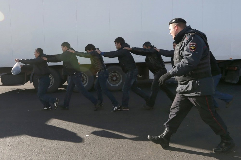 Russian police officers detain alleged illegal migrants during a raid at a vegetable warehouse in Moscow, October 2013. Photo: EPA/MAXIM SHIPENKOV