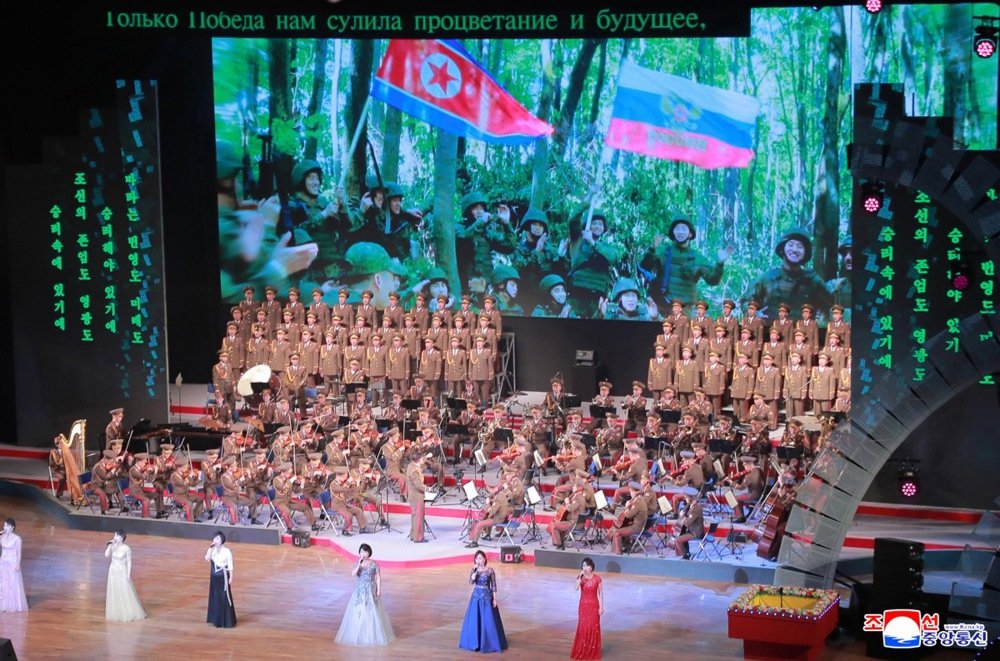 North Korean artists perform during a concert while a video shows soldiers holding Russian and North Korean flags, during a visit of Russian Culture Minister Olga Lyubimova to Pyongyang on 29 June 2025. Photo: EPA/KCNA